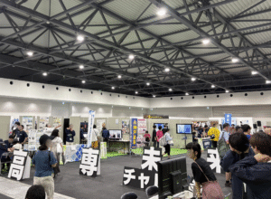 大阪関西万博のWASSE会場でで実施された「高専未来チャレンジ」の会場全体の様子。20校からブースを出展し、各校の研究で活躍する教員・学生が一般来場者に研究の成果を発表するシーンが映っています。